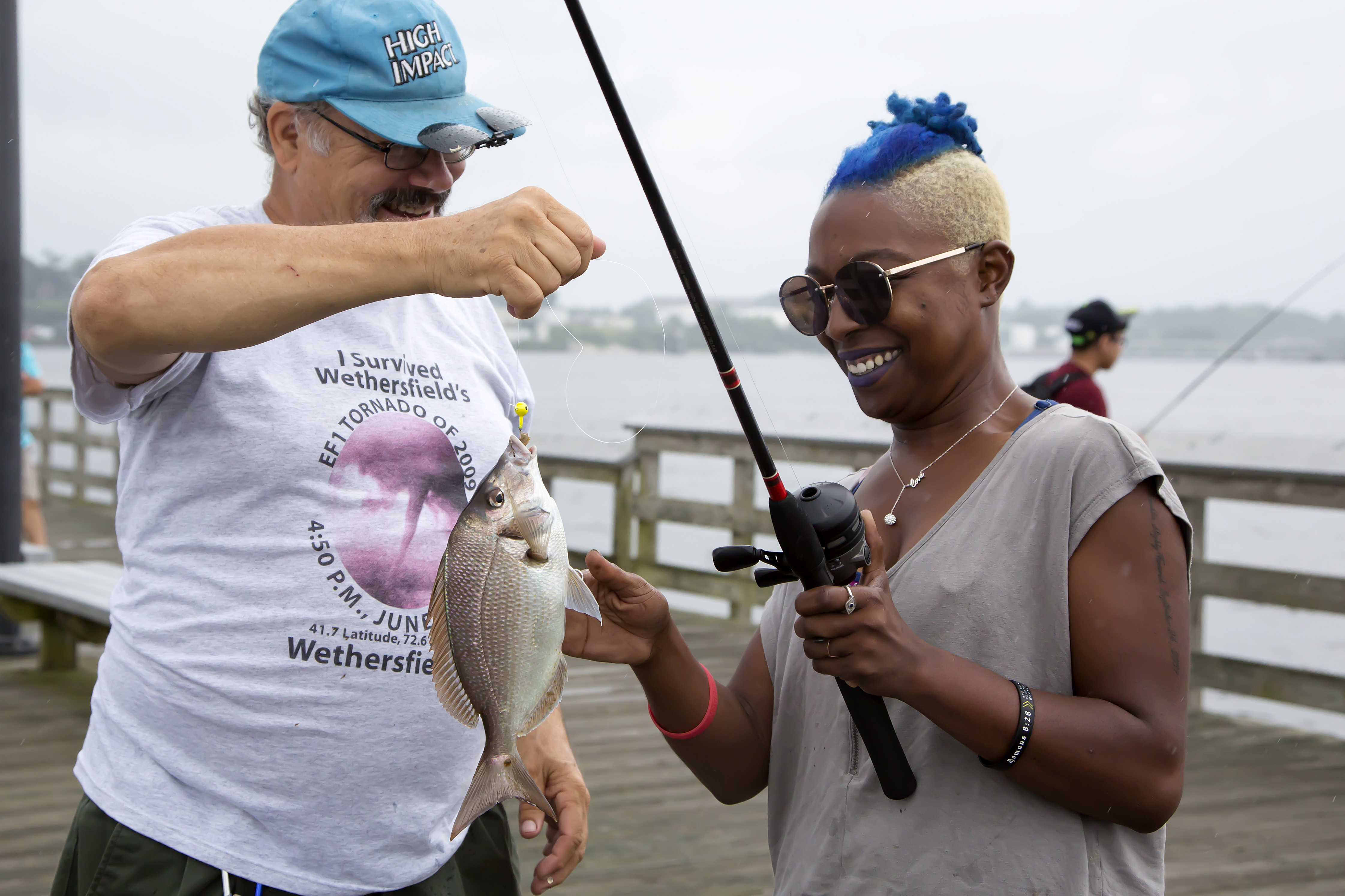 New angler catching a scup with a CARE fishing instructor on saltwater fishing day.