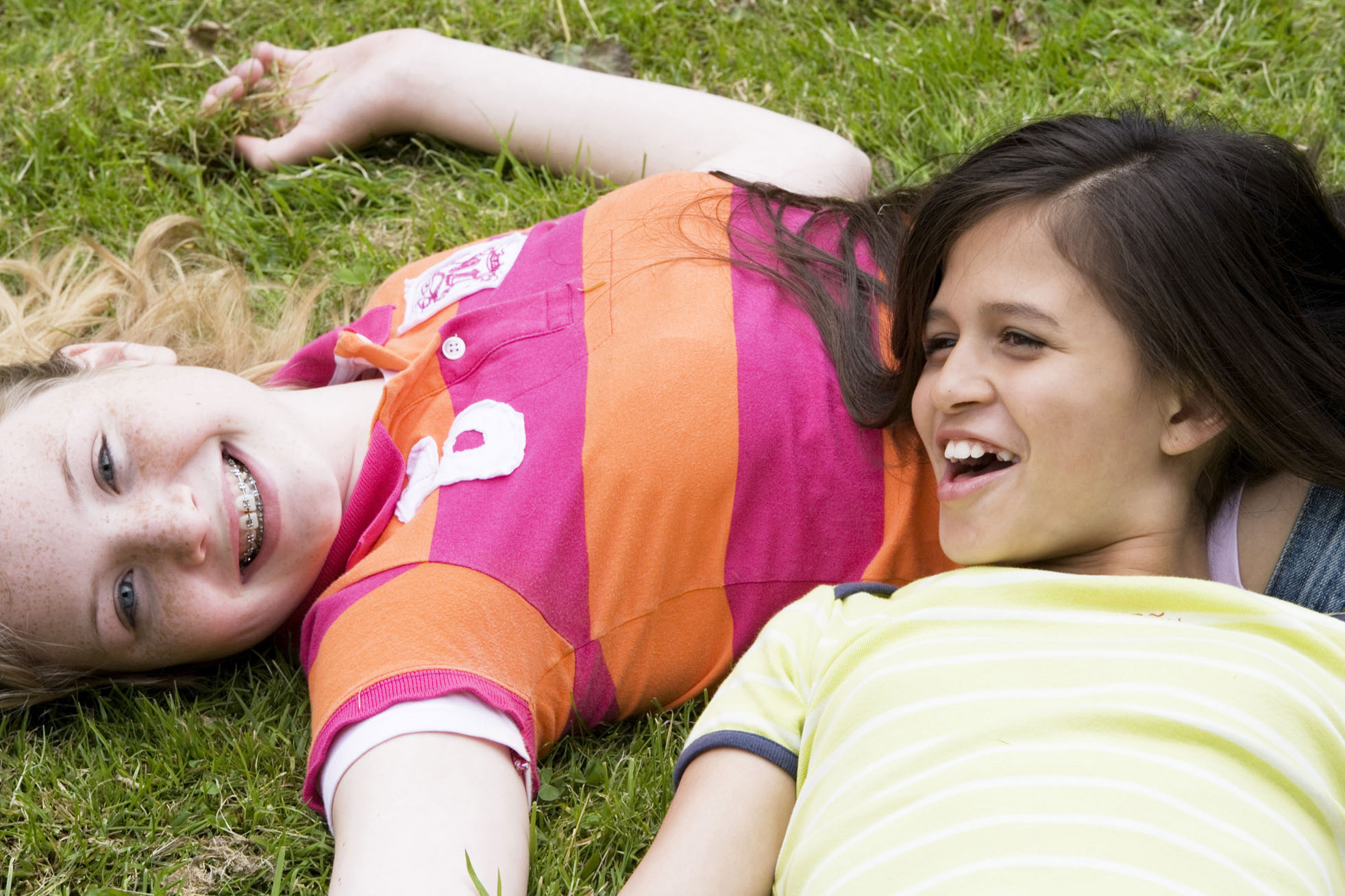 two students laying in the grass and smiling